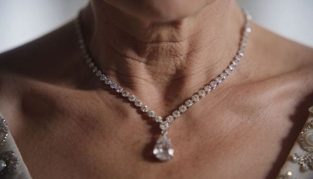 Senior woman wearing diamond tennis necklace with pear pendant close-up on neckline and collarbone