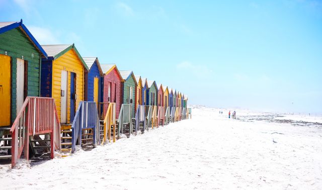 Vibrant beach huts lined up along a sunny ocean shore, perfect for travel and tourism promotions, coastal living blogs, and summer vacation advertisements.