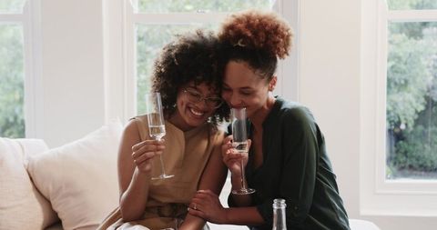 African American Couple Celebrating with Champagne on Minimalist Sofa, Intimate Toast