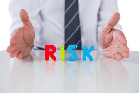 Businessman Gesturing Beneath Transparent Risk Concept on Desktop