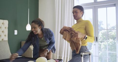 Diverse Women Packing for Trip in Bright Bedroom