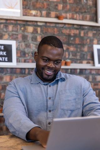 Focused african american entrepreneur working on laptop in cozy workspace