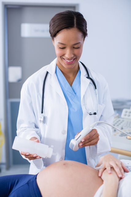 Healthcare professional performing ultrasound on pregnant woman in hospital. Useful for topics related to pregnancy, prenatal care, medical examinations, and healthcare services. Ideal for medical websites, health blogs, educational materials, and hospital brochures.