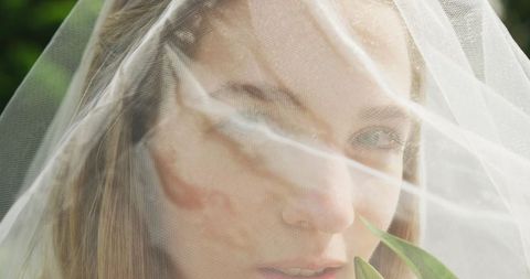 Bride with veil on sunny outdoor wedding day