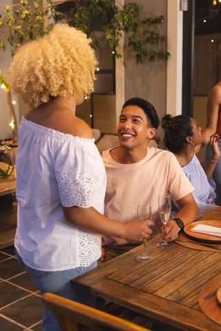 Friends celebrating dinner toast on outdoor patio with warm lighting intimate conversation