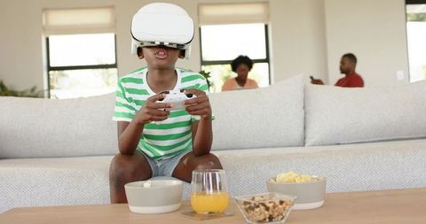 Child Playing Virtual Reality Game with Controller as Family Relaxing in Modern Living Room