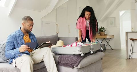 Couple Packing Suitcase for Holiday in Cozy Living Room
