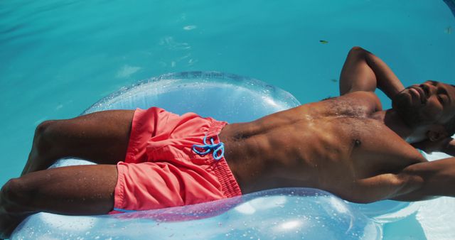 Handsome african american man lying on inflatable sunbathing in swimming pool. staying at home in isolation during quarantine lockdown.