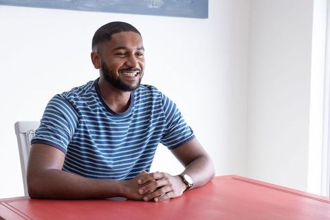Friendly professional man smiling at red table in modern office