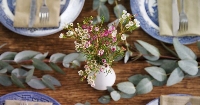 A rustic table setting features elegant china and a delicate floral centerpiece, with copy space. The arrangement creates a warm, inviting atmosphere for a meal or gathering.