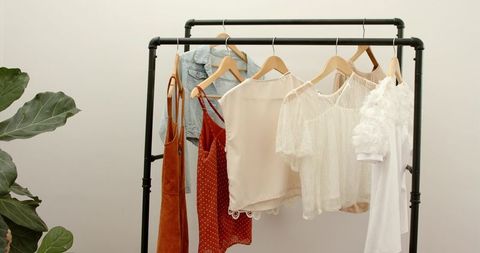 Minimal boutique clothing rack displaying neutral blouses, lace tops and denim jacket