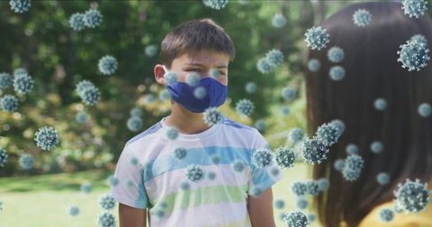 Masked boy wearing blue mask talking to friend outdoors with virus particles overlay