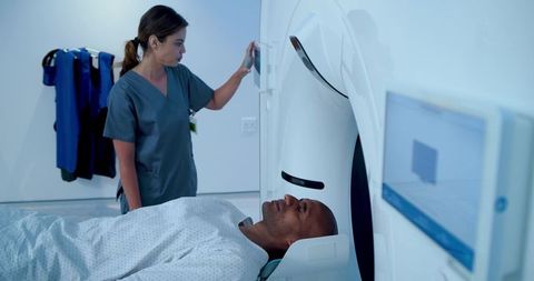 Female radiologic technologist operating ct scanner while male patient undergoing head scan