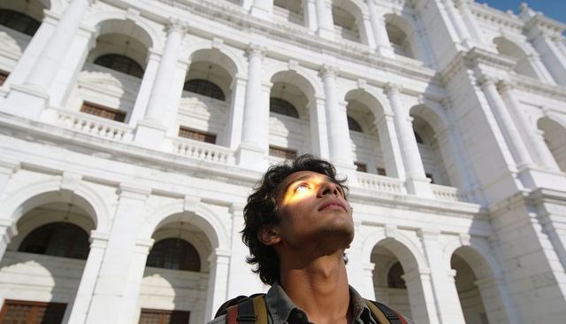 Young asian traveler gazing at white neoclassical building with arched facade