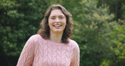 Joyful Woman Smiling Outdoors in Pink Sweater