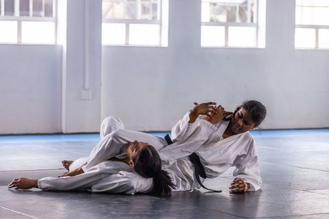 Two women practicing brazilian jiu-jitsu armbar technique