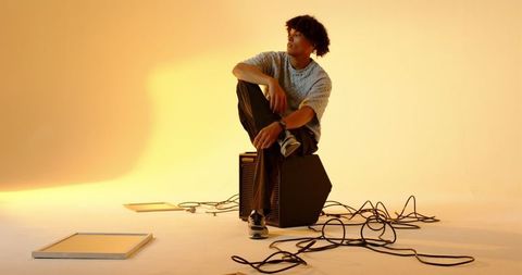 Musician Sitting on Amplifier in Creative Studio Ambiance
