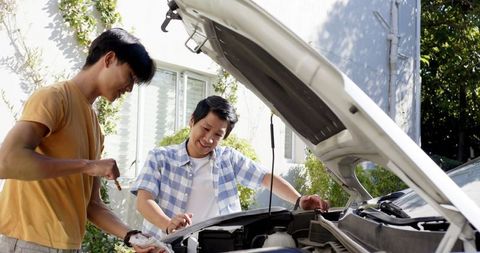 Father mentoring son in car maintenance outdoor scene