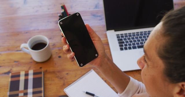 Woman Holding Smartphone at Desk with Coffee and Notebook - Download Free Stock Images Pikwizard.com