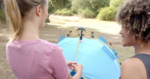 Two women assembling tent outdoor adventure