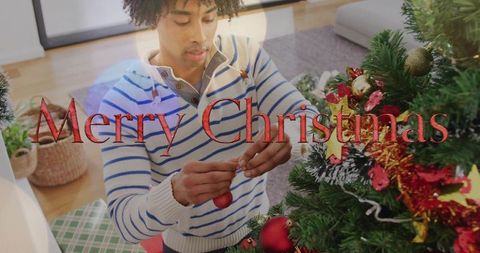 Black man decorating christmas tree with red bauble in cozy living room holiday scene
