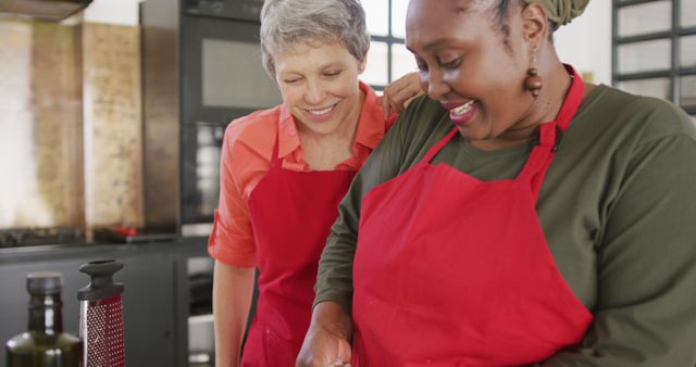 Cheerful Women Wearing Red Aprons Cooking Together in Modern Kitchen - Download Free Stock Images Pikwizard.com