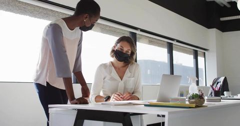 Colleagues collaborating with masks in modern office environment