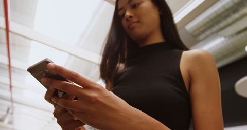 Focused Asian Woman Using Smartphone in Modern Office