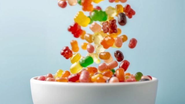 Gummy bears and jelly beans pouring into bowl