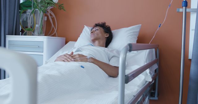 Image depicts a patient lying on a hospital bed against an orange wall, suggesting recovery and healthcare environment. Can be used for healthcare, medical articles, or insurance publications. Suitable for illustrating hospital care, patient recovery, or healthcare services.