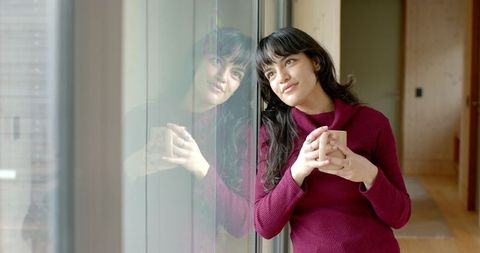 Woman Relaxing with Coffee Mug at Home Window