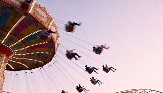 Sunset swing carousel spinning with riders in motion blur and glowing vintage lights