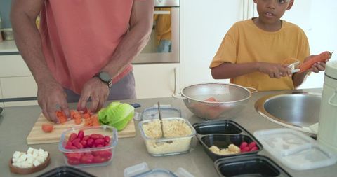 African american father and son preparing healthy family meal in bright modern kitchen