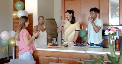 Friends Toasting with Drinks Celebrating in Modern Kitchen