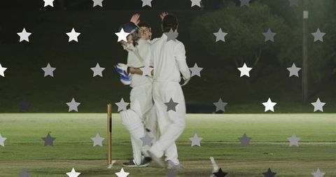 Night cricket team celebrating wicket with star overlay under bright floodlights