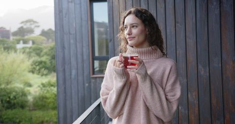 Woman Enjoying Herbal Tea on Wooden Balcony in Nature Setting