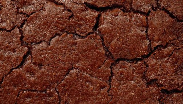 Cracked Chocolate Brownie Surface Macro Texture Showing Glossy Crust, Fissures, Crumbs
