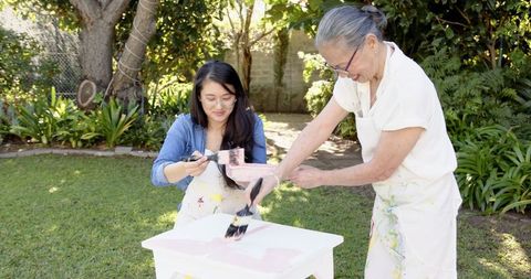 Family diy project: mother and daughter painting in backyard