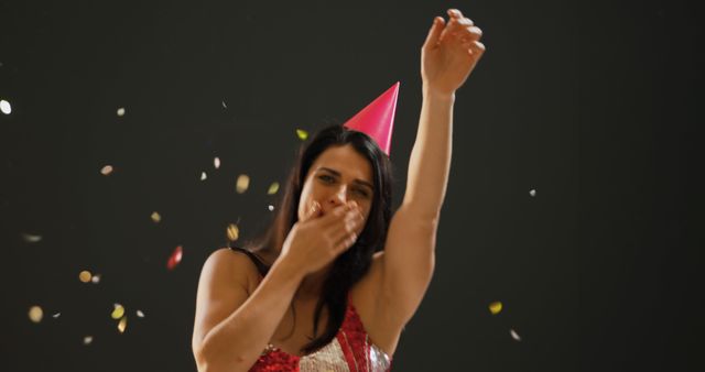 Caucasian woman celebrates joyfully at a party, with copy space. Confetti adds a festive touch as she dances and enjoys the moment.