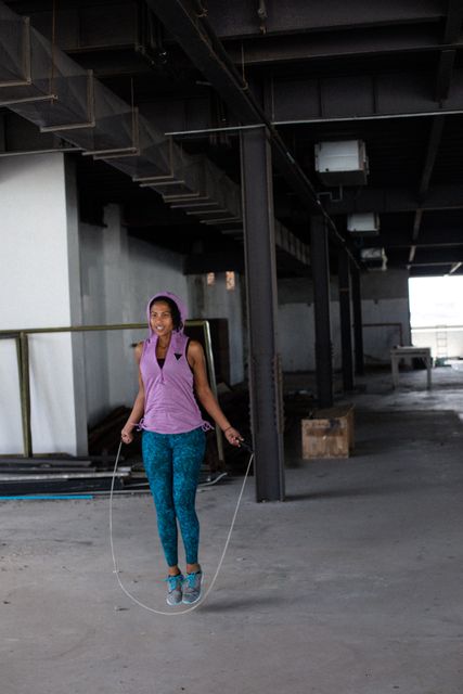 African american woman wearing sports clothes skipping the rope in empty urban building - Download Free Stock Photos Pikwizard.com