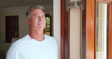 Senior Man Relaxing Near Window Observing Outdoors