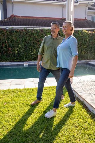 Senior Couple Strolling by Poolside Garden