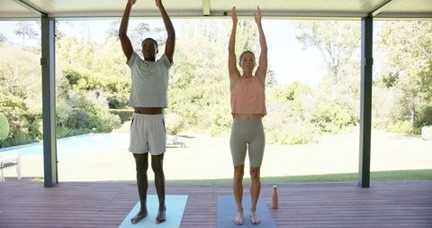 Diverse couple practicing yoga on outdoor patio in serene setting