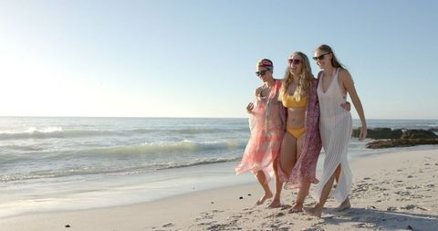 Three Young Women Enjoy Sunny Beach Day in Swimwear