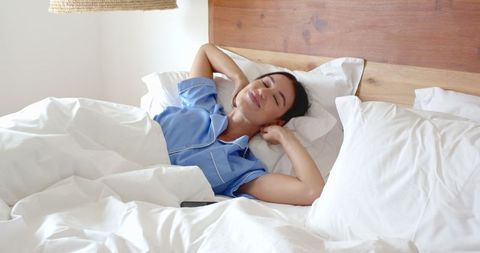 Woman Relaxing Comfortably in Bed in Blue Pajamas