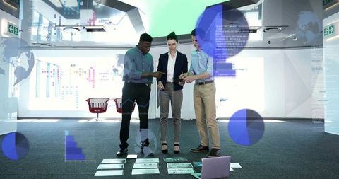 Multicultural team collaborating on data visualizations on floor with tablets and laptop