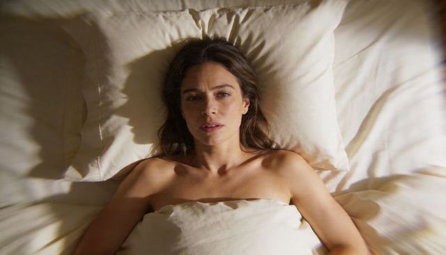 Woman lying in bed contemplating at dawn, calm morning wellness and sleep concept
