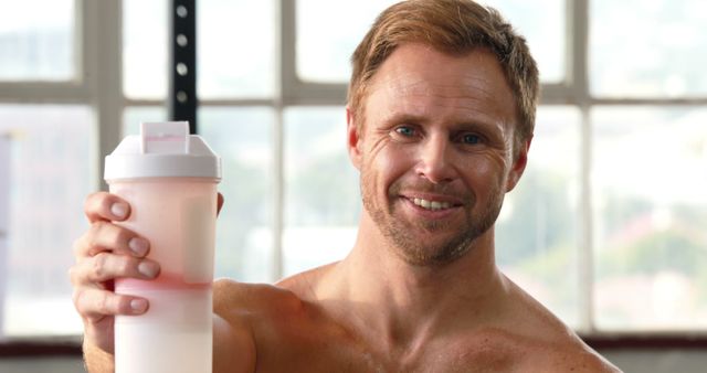 Smiling Fit Man Holding Protein Shake in Gym Environment - Download Free Stock Images Pikwizard.com