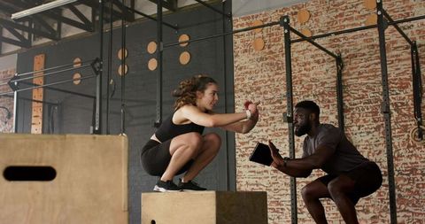 Personal trainer coaching client with tablet in modern gym