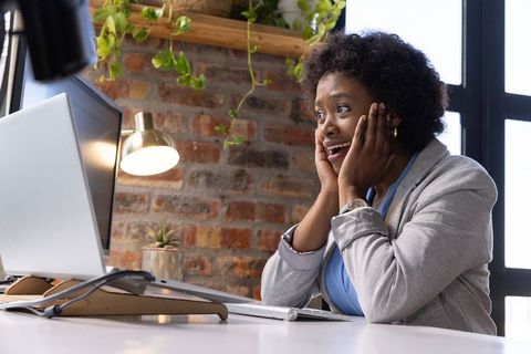 Surprised African American Woman at Office Desk with Computer